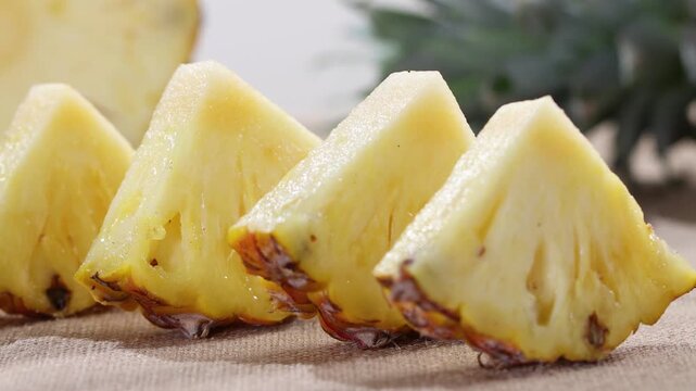 Fresh juicy pineapple slices arranged in a row on a rustic cloth background