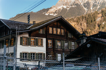 Scenic alpine village with traditional houses and green pastures set against dramatic mountains and rocky cliffs in a peaceful rural landscape. © Христя Сидор