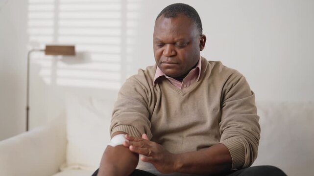 Portrait of middle-aged man unpacking and sticking nicotine patch on arm. Innovative transdermal patch for curing nicotine addiction and inputting medicine in blood, modern technology of medicine