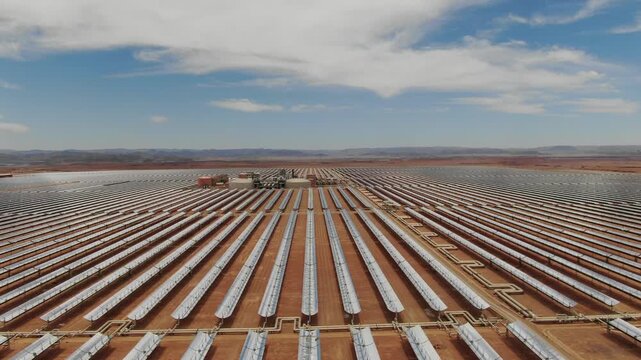 Aerial view of symmetrical solar mirror rows leading toward the Noor solar power plant in Ouarzazate Morocco showing large scale renewable energy in the desert.