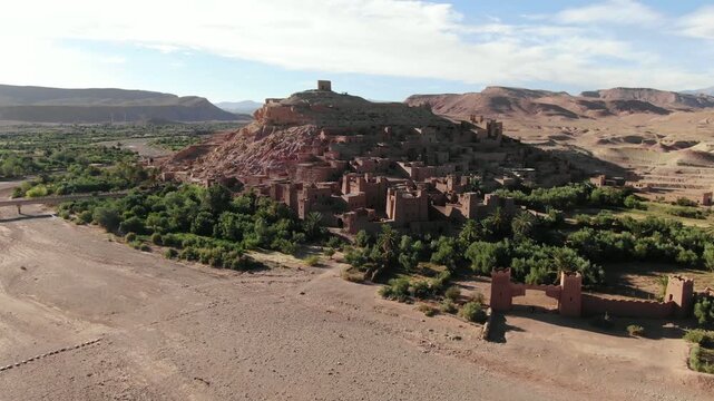 Aerial drone view of the historic Ait Benhaddou kasbah, ancient clay fortress village and UNESCO World Heritage site near Ouarzazate in southern Morocco surrounded by desert landscape.