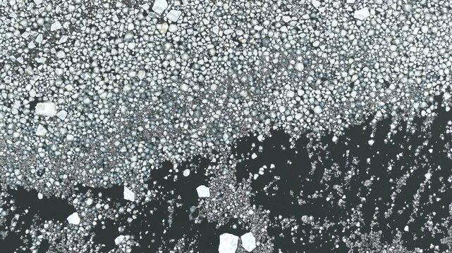 Aerial top down backdrop of floating sea ice and dark water forming an abstract winter texture pattern