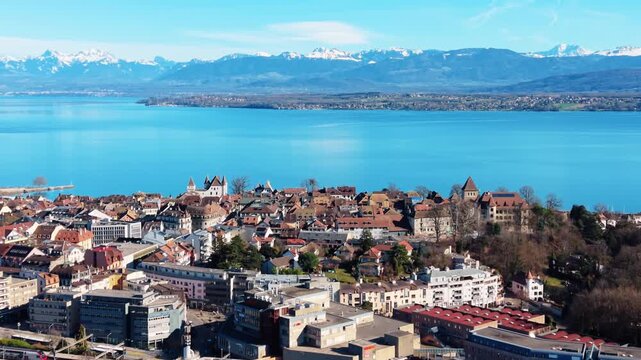 Push in drone shot of Lake Geneva and Nyon cityscape during the day in Canton of Vaud, Switzerland