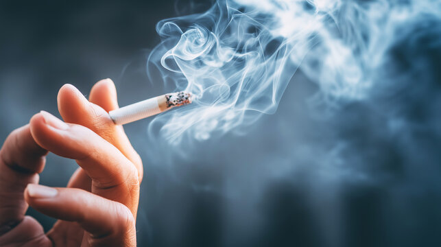 Hand holding a burning cigarette with smoke against a dark background, illustrating common themes of nicotine addiction and unhealthy habits