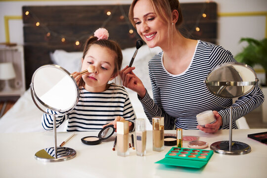 Mother and daughter applying make up together