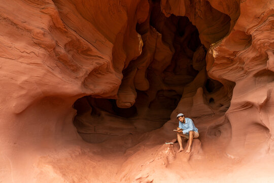 Young man sitting in a cave, taking notes