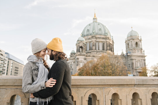 Young couple embracing with Berlin Cathedral in background, Berlin, Germany