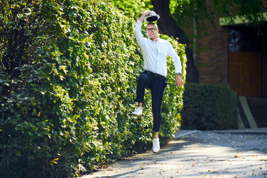 Happy young man jumping around at a hedge