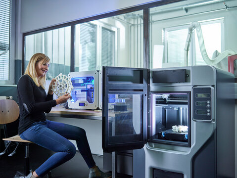Female technician checking turbine wheel being printed with 3D printer