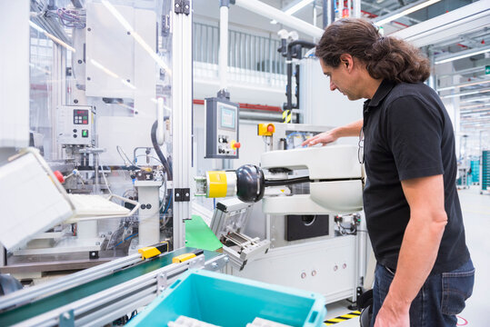 Man with assembly robot in factory
