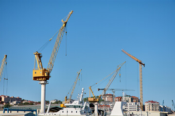 Fototapeta premium Yellow shipyard crane towering under clear blue sky in Vigo industrial port