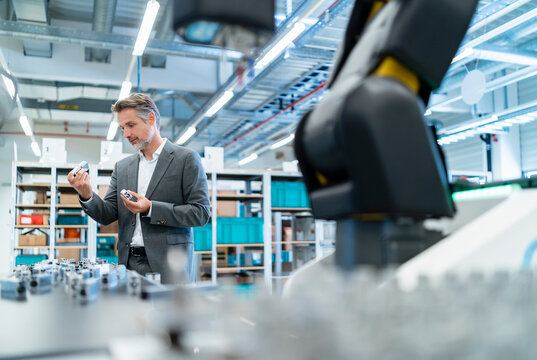 Businessman examining workpieces in a modern factory hall