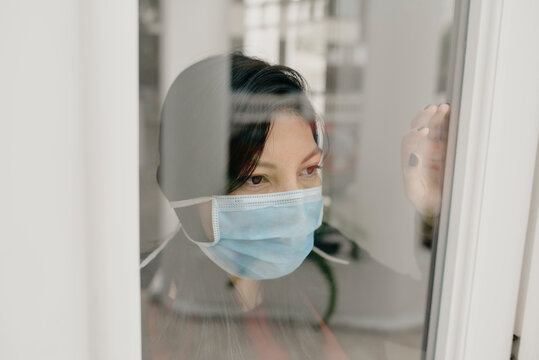 Portrait of with protective mask at window pane