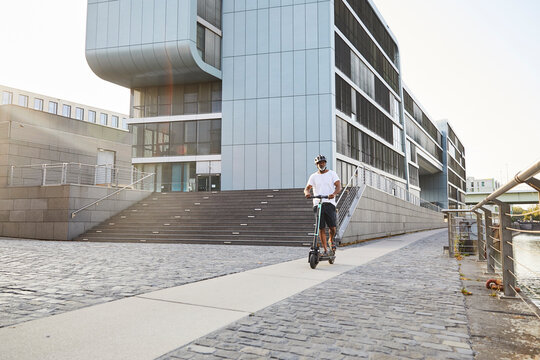 Smiling mature man riding E-Scooter in summer
