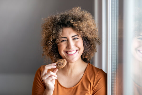 Smiling mid adult woman eating a cookie