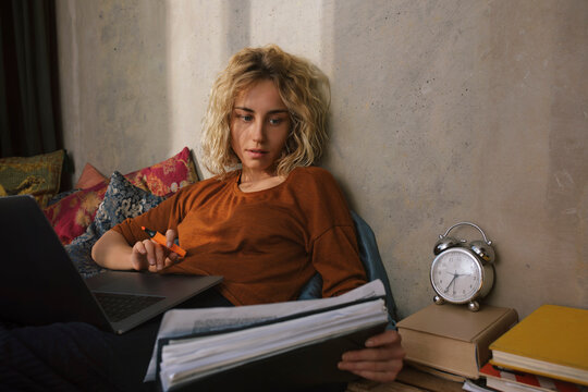 Portrait of blond student on bed working on laptop