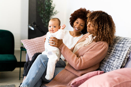 Smiling family sitting with baby girl on sofa at home
