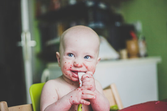 Smiling baby boy making mess while eating