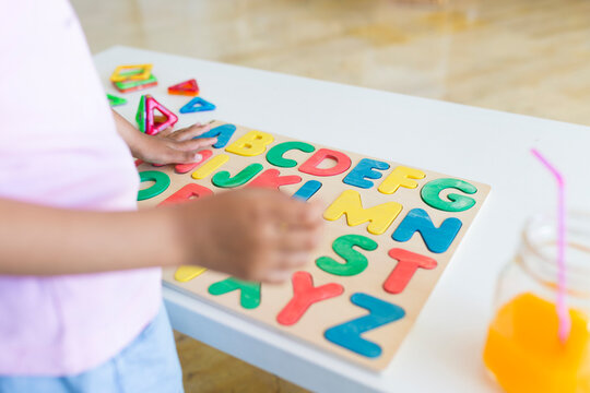 Close-up of girl playing with alphabet learning game on table