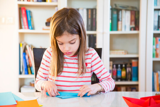Girl tinkering with paper on table at home