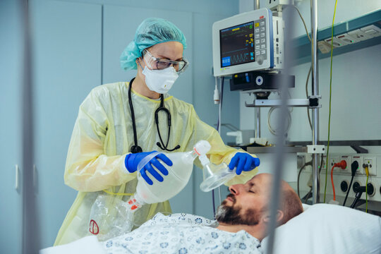 Doctor with bag valve mask caring for patient in emergency care unit of a hospital