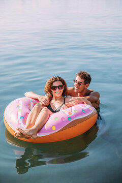 Happy young couple bathing in the sea on inflatable float in donut shape