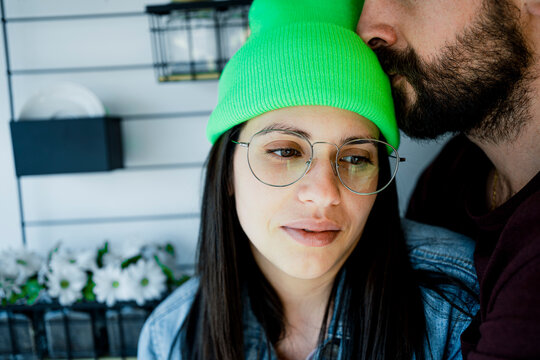 Thoughtful woman being kissed by man on forehead at home