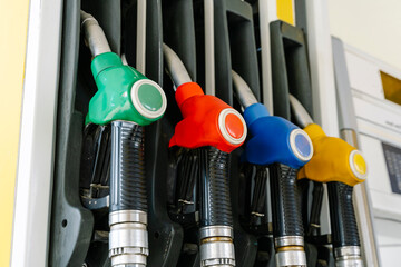 Fototapeta premium Fuel pump nozzles hanging at a modern gas station during a period of high oil prices. A conceptual photography showcasing the global energy crisis, increasing gasoline costs