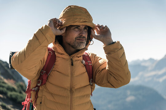Austria, Tyrol, portrait of man with hooded jacket on a hiking trip in the mountains