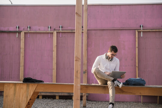 Young man sitting on platform using tablet
