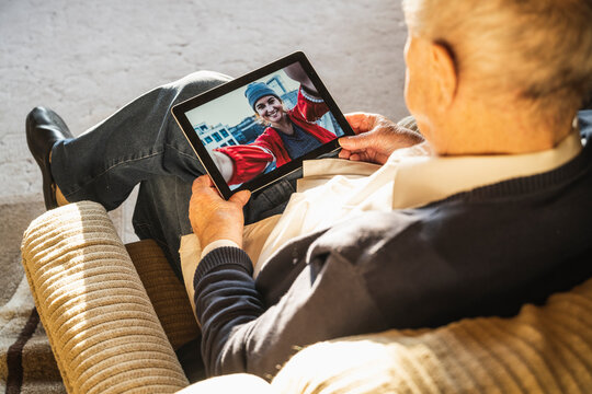 Grandfather talking with granddaughter on video call through digital tablet at home
