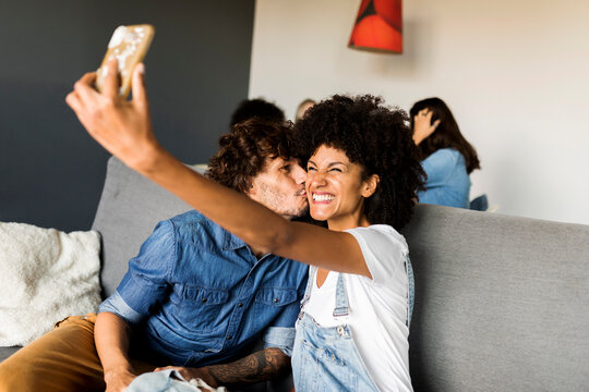 Happy couple sitting on couch taking a selfie