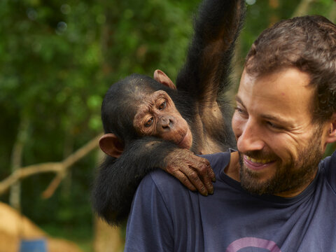 Cameroon, Pongo-Songo, Smiling man with Chimpanzee (Pan troglodytes) on back