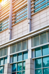Fototapeta premium Office building facade featuring glass windows and louvers