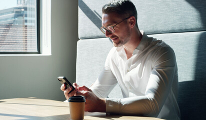 Happy, businessman and typing with phone in office booth for conversation or social media. Man,...
