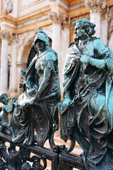 Statues of figures sitting on a railing in a historical location during daytime