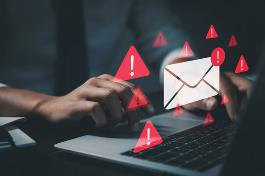 A businessman typing on a laptop with warning email icons, illustrating email threats, phishing attacks, malware, and data breaches for cybersecurity alerts