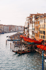 Fototapeta premium Gondolas float in the canal near restaurants and buildings in Venice during the late afternoon