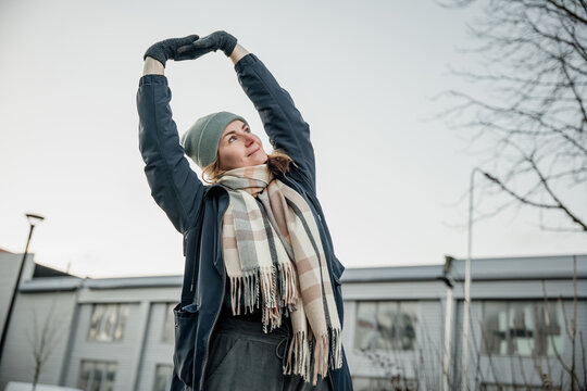 Young person stretches in cold weather outside a building during daytime in winter