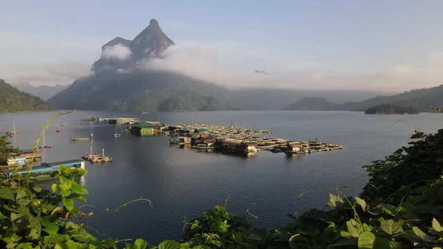 Aerial drone view of Ta Dung Lake with floating houses and fish farms surrounded by mountains and calm water in Dak Nong province Vietnam