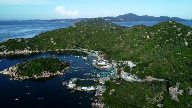 Aerial drone view of Cai Beo floating village with fish farms boats and houses along calm bay surrounded by green hills in Lan Ha Bay near Cat Ba Island Vietnam