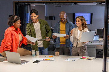 Diverse coworkers in blazers reviewing pages and tablet while discussing monitor chart at office © wavebreak3