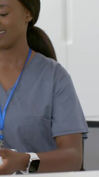 Vertical video: Receiving offered reader, staff in gray scrubs with lanyard holding phone to scan