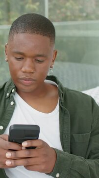 Vertical video: Scrolling pierced man in green shirt answering ringing black phone on sofa at home