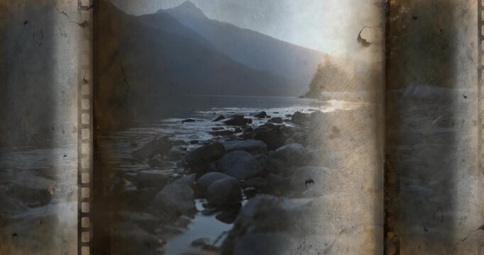 Rocky shore and pools sitting under film, sprocket showing, light leak moving, evoking aged reel