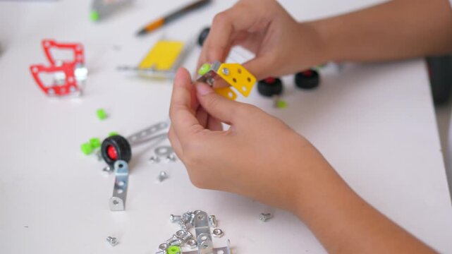 Close up of child hands assembling 3D printed robot model on table. Concept of STEM education, robotics learning, creativity, and technology development