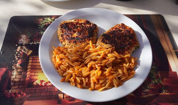 Grilled chicken patties with orzo pasta, served in a restaurant in Greece
