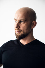 Fototapeta premium Man with bald head and beard looks to the side in bright indoor setting