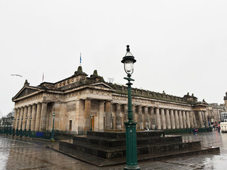 Naklejka premium Neoclassical municipal National Gallery building with columns and lamppost on wet plaza in Edinburgh, Scotland, UK, historic architecture and urban landmark in overcast weather