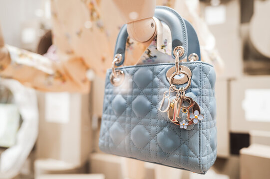 Luxury Lady Dior Handbag with Flower Charms on Display in Boutique Window. the prestige and elegance of French haute couture in a modern Asian shopping district.